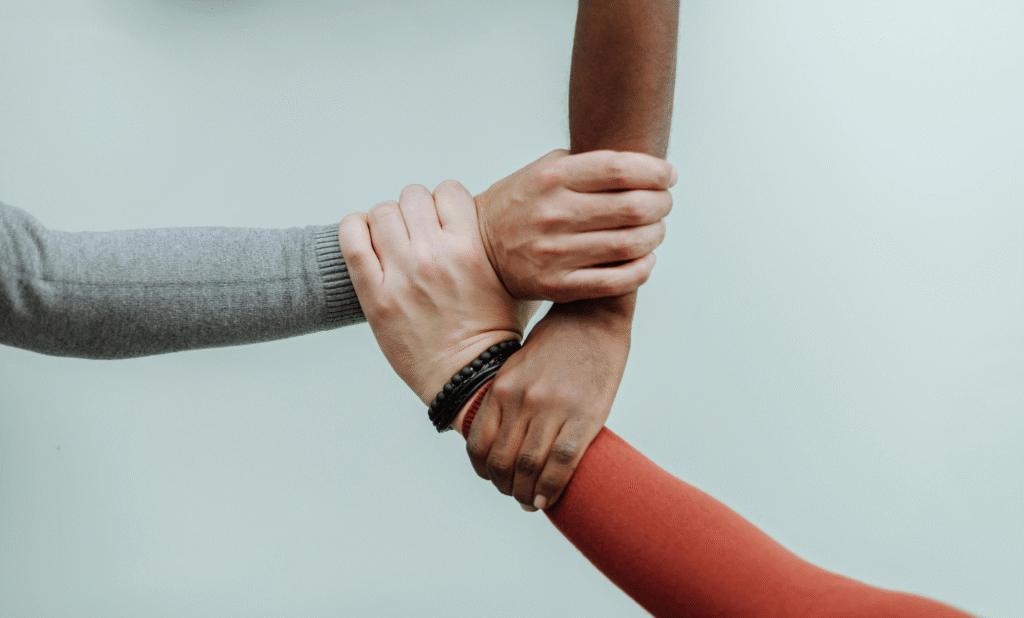 Hände von drei Personen greifen ineinander